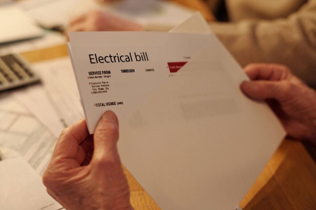 A hand holding and reading the electric bill.